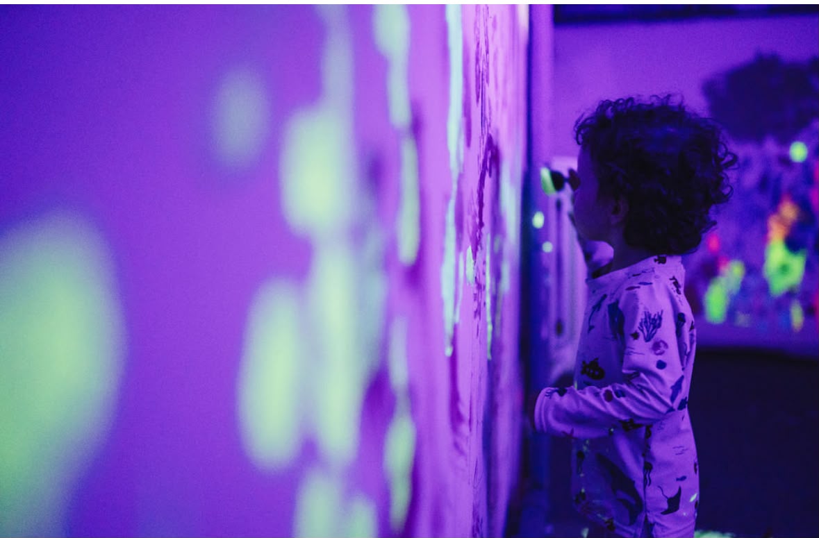 Dziecko przy świecącej ścianie pod blacklight